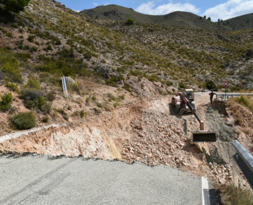 Imagen de los trabajos que se están realizando con una máquina excavadora acercando material para levantar un muro en la parte inferior de la ca ...