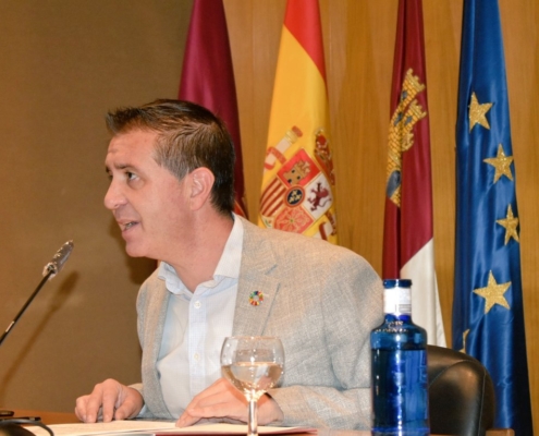 El presidente de la Diputación, en Salón de Actos de la institución, hablando al micrófono; tras él, las banderas oficiales