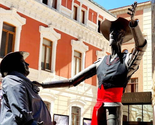 En primer plano, las estatuas de Don Quijote y Sancho Panza con vestimenta típica manchega, a la entrada al Palacio de la Diputación de Albacete