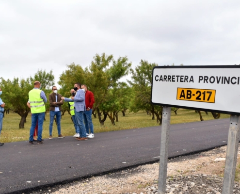 Primer plano del cartel informativo de la AB.217 y al fondo los responsables políticos de la Diputación, el Ayuntamiento de Alpera y diferentes  ...