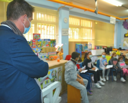 De espaldas, el presidente de la Diputación escucha al alumnado del colegio 'La Paz' de Albacete cantando villancicos