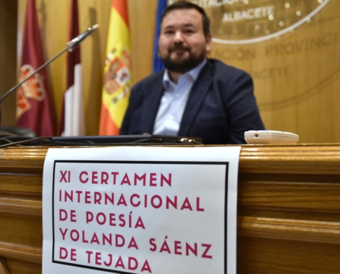 Primer plano del cartel del XI Certamen Internacional de Poesía Sáenz de Tejada con la imagen de fondo y en desenfoque del vicepresidente provin ...