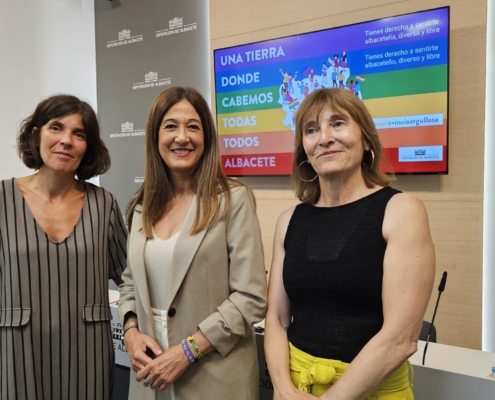 Pilar Callado posa con el equipo de la Unidad de Igualdad en la sala de prensa ante la imagen de las actividades con motivo del Orgullo 2024