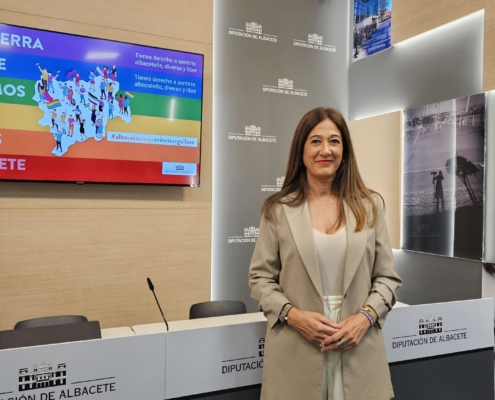 Pilar Callado posa en la sala de prensa ante la imagen de las actividades con motivo del Orgullo 2024